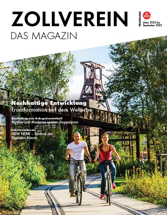 Titelbild des Magazins Zollverein Das Magazin, Ausgabe 01/2023, gültig von März bis September 2023. Im Vordergrund fahren ein Mann und eine Frau bei sonnigem Wetter nebeneinander mit Fahrrädern auf einem begrünten Gleisweg. Sie wirken sportlich und entspannt. Im Hintergrund erhebt sich das ikonische Fördergerüst der Zeche Zollverein, umgeben von dichtem Grün und Bäumen. Auf dem Cover sind Themen wie nachhaltige Entwicklung, eine Ausstellung zum Ruhrgebietsfußball und das Festival der digitalen Künste NEW NOW angekündigt. Die Szene vermittelt aktive Freizeitgestaltung in postindustrieller Kulturlandschaft.