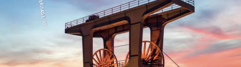 Titelseite eines Sales Guides für das UNESCO World Heritage Site Zollverein. Im Vordergrund ist der markante Förderturm der Zeche Zollverein bei Sonnenuntergang zu sehen, warm beleuchtet vor einem blau-orangefarbenen Himmel. Oben rechts stehen das Zollverein-Logo und der Hinweis auf 25 Jahre UNESCO-Welterbe.